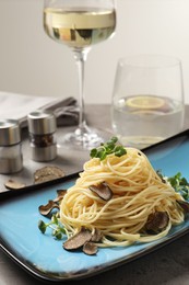 Photo of Delicious pasta with truffle slices and microgreens served on light grey table