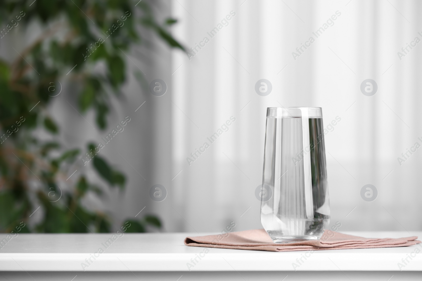 Photo of Glass of pure water on white table indoors, space for text