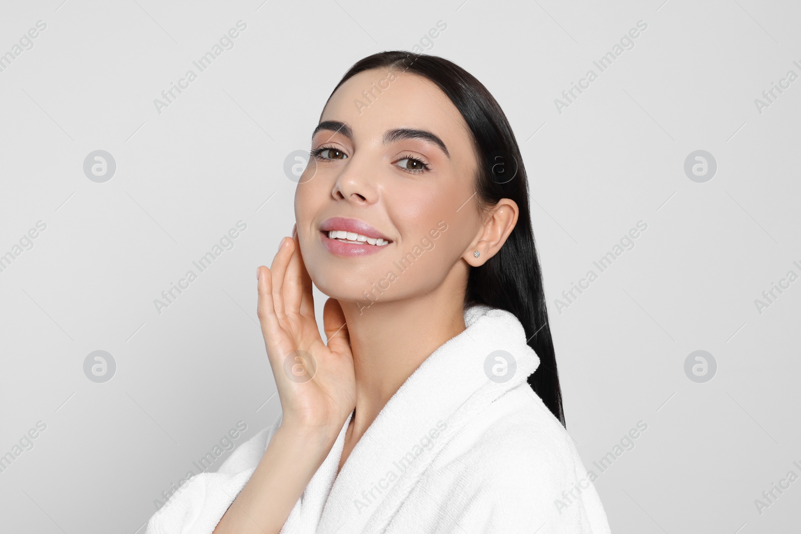 Photo of Portrait of attractive young woman in bathrobe on light grey background. Spa treatment