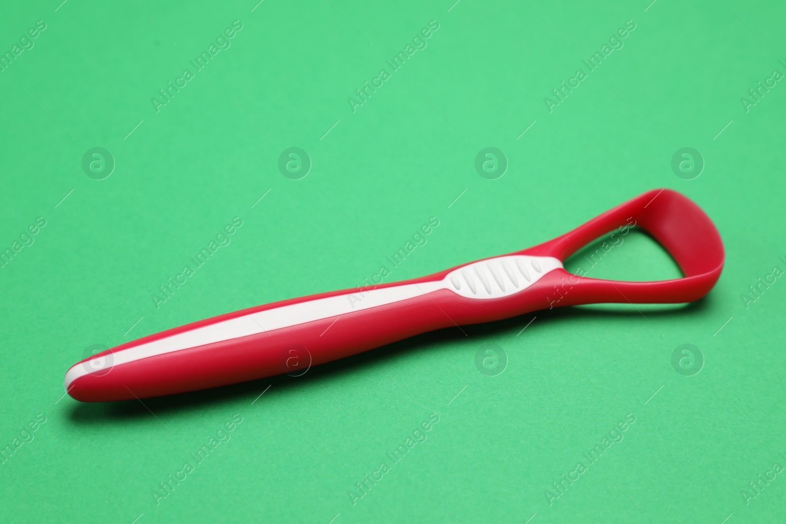 Photo of One red tongue cleaner on green background