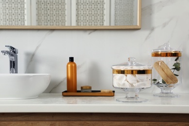 Jars with cotton pads and loofah sponges on bathroom countertop