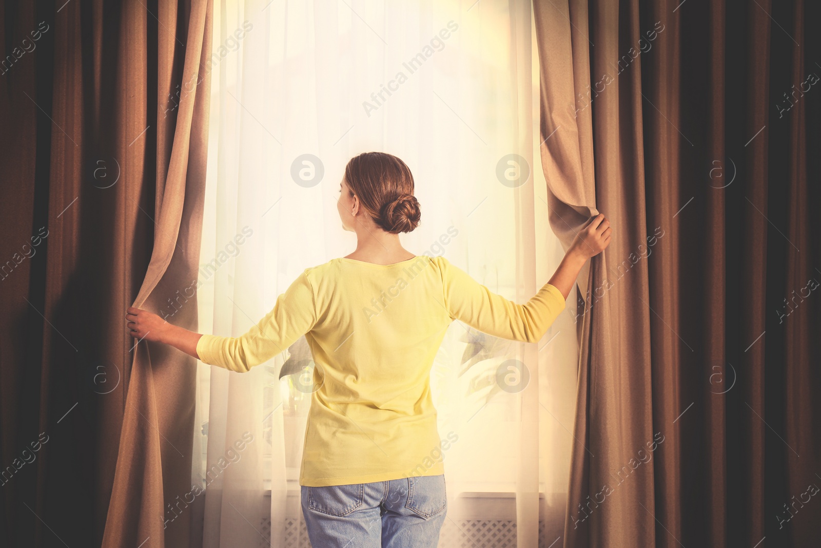 Image of Woman opening window curtains at home in morning