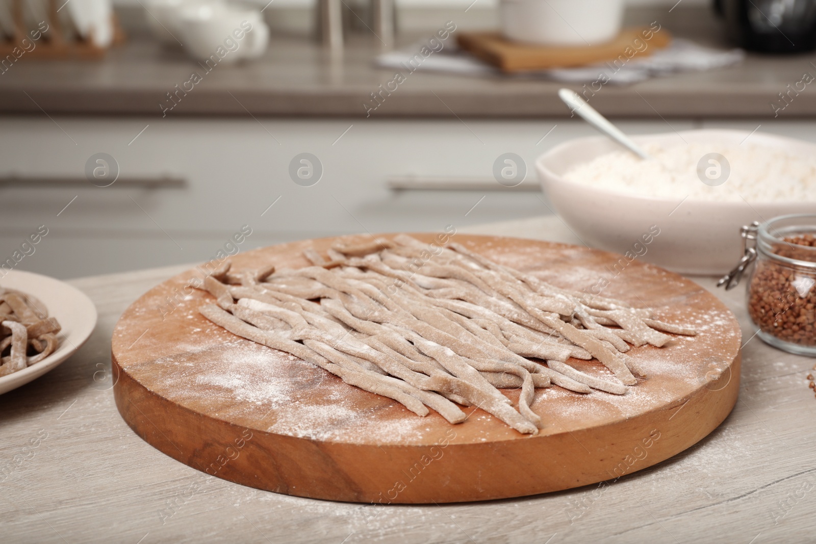 Photo of Uncooked homemade soba (buckwheat noodles) on wooden table in kitchen, closeup