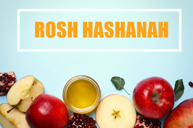 Image of Honey, apples and pomegranates on light blue background, flat lay. Rosh Hashanah holiday