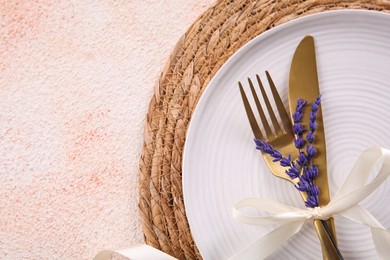Cutlery, plate and preserved lavender flowers on color textured table, top view. Space for text