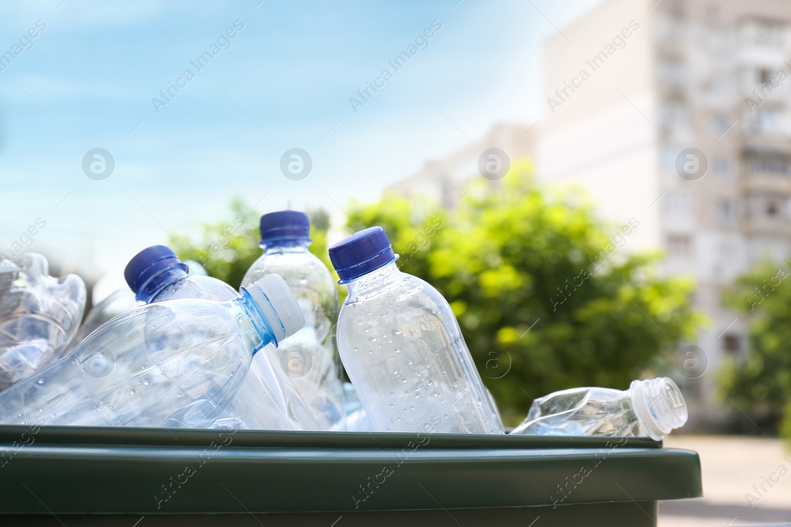 Photo of Many used plastic bottles in trash bin outdoors, closeup. Recycling problem