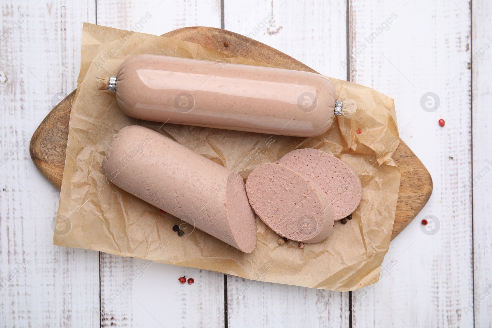 Photo of Board with delicious liver sausage on white wooden table, top view