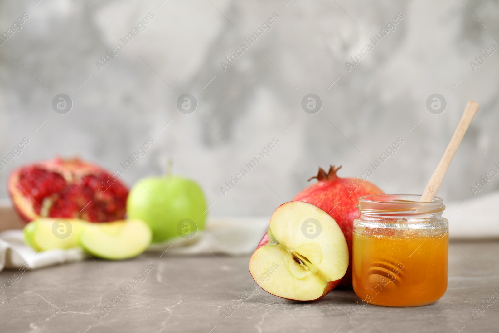 Photo of Honey, apples and pomegranate on marble table, space for text. Rosh Hashanah holiday