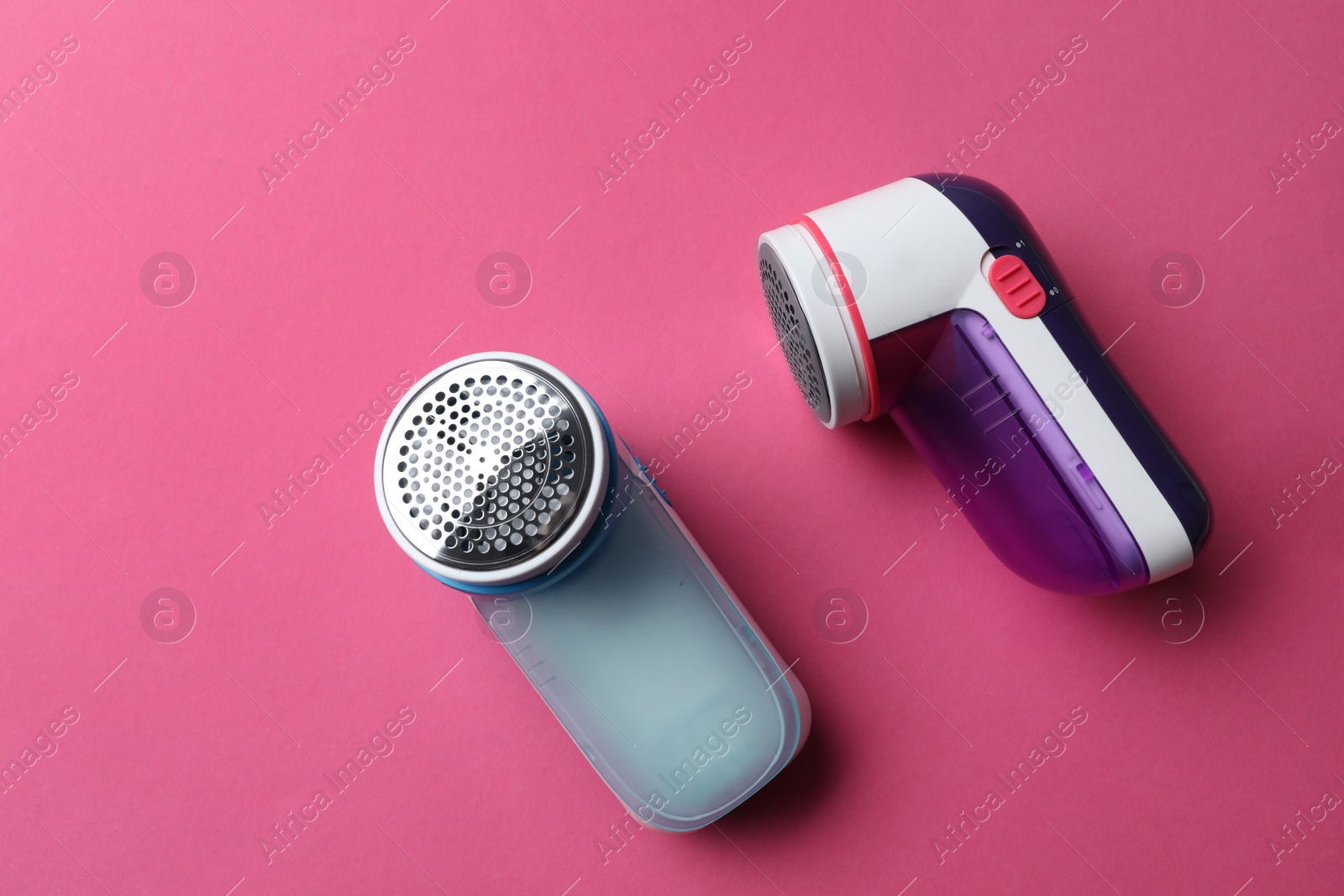 Photo of Modern fabric shavers on pink background, flat lay