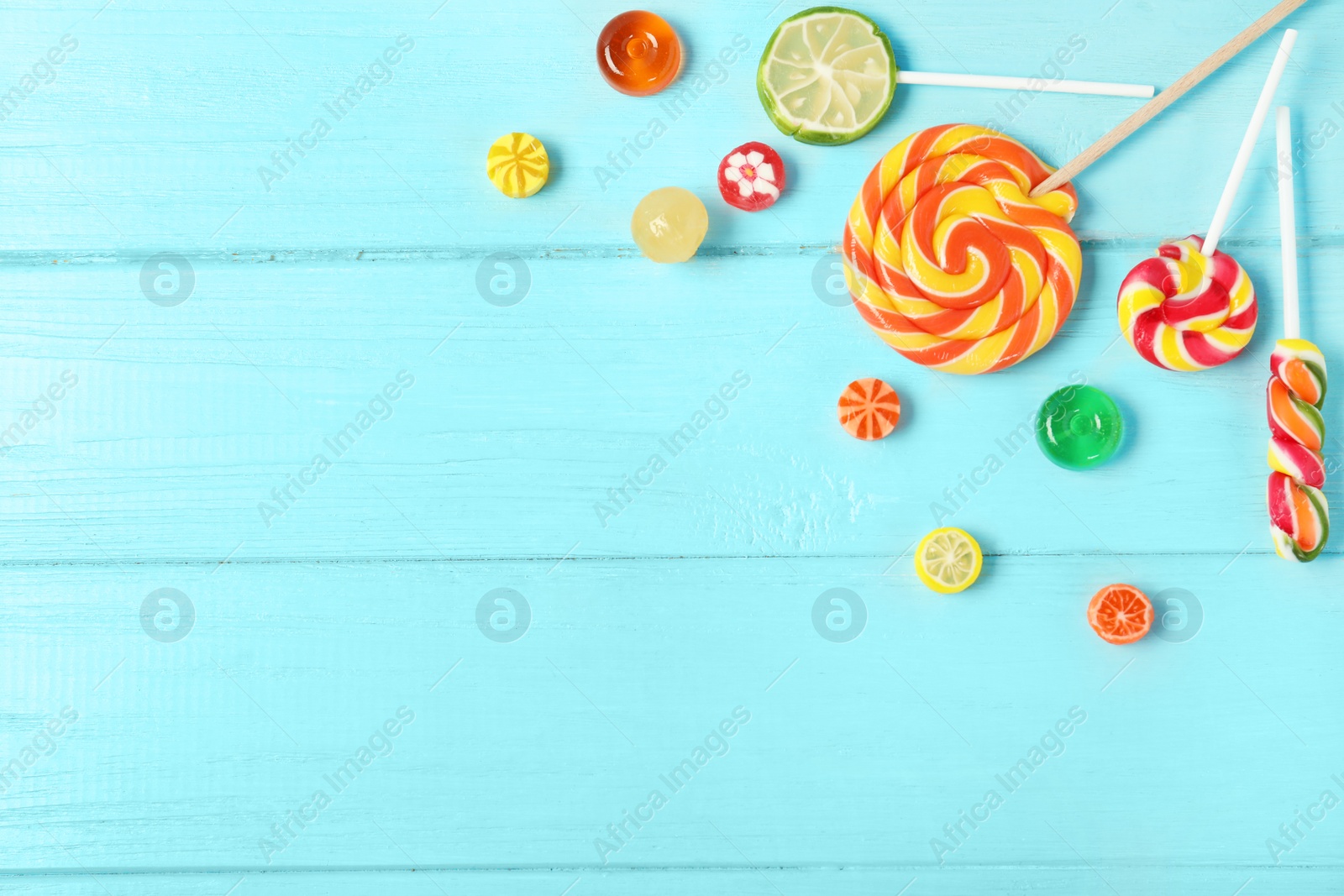 Photo of Flat lay composition with different candies and space for text on color wooden background