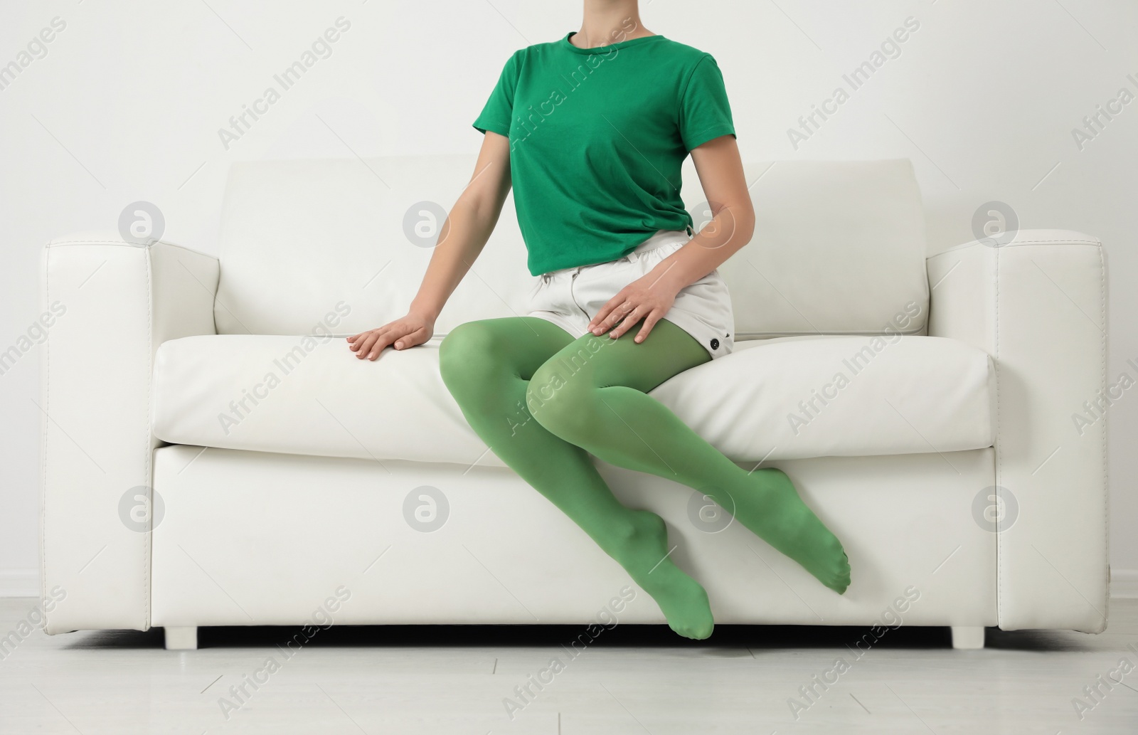 Photo of Woman wearing green tights sitting on sofa indoors, closeup