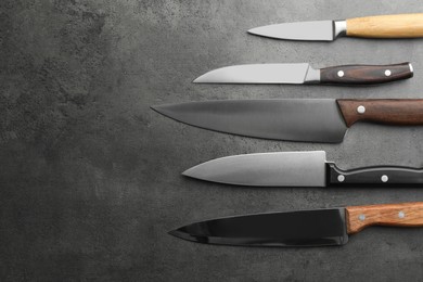 Photo of Many different knives on grey textured table, flat lay. Space for text