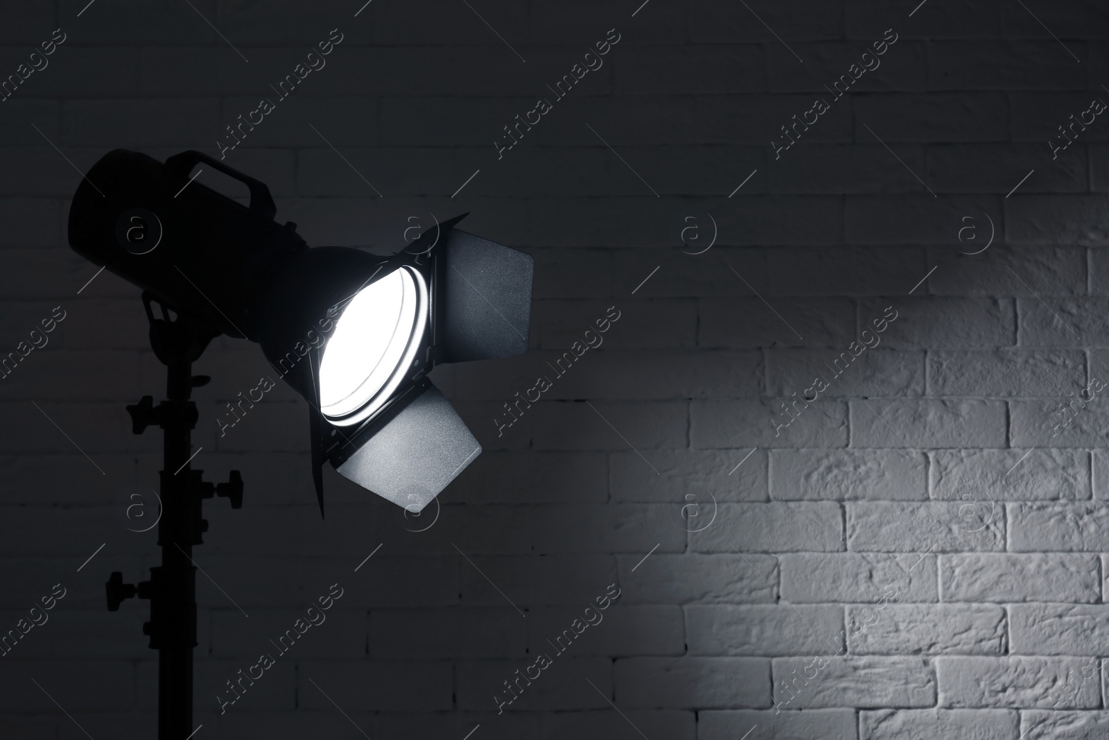 Photo of Professional photo studio lighting equipment near brick wall. Space for text