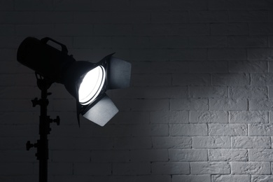 Professional photo studio lighting equipment near brick wall. Space for text