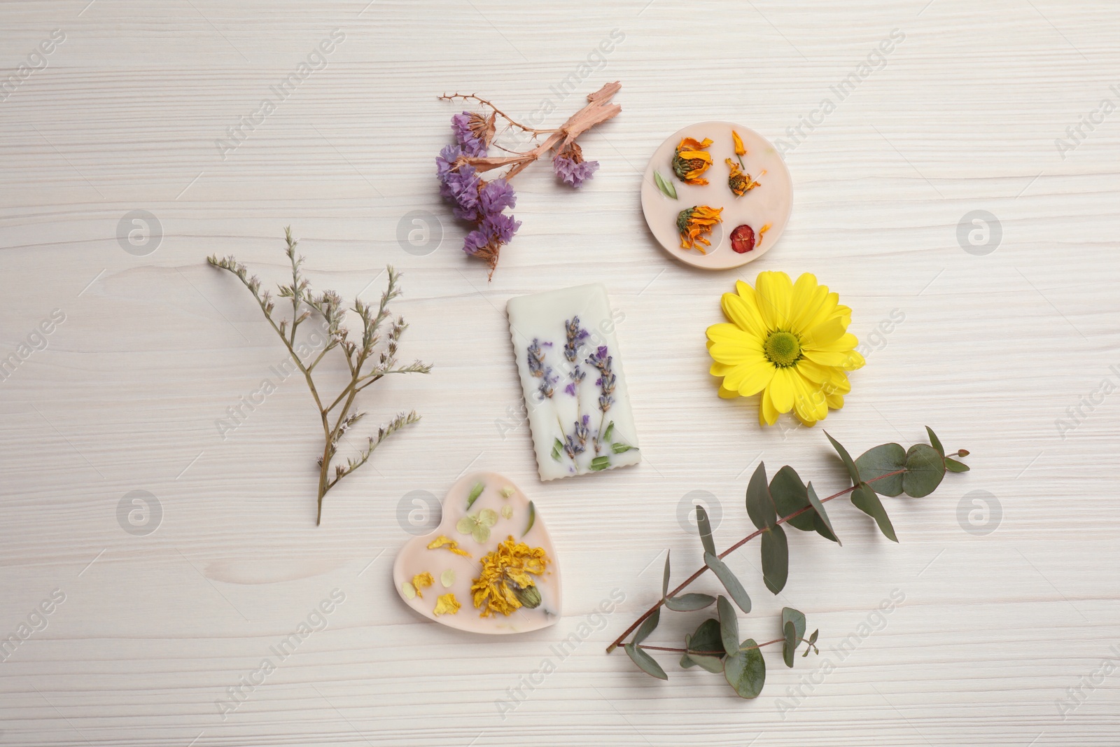 Photo of Beautiful scented sachets and flowers on white wooden table