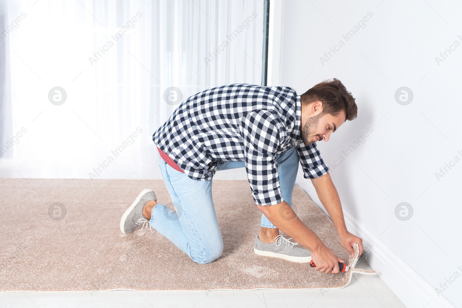 Photo of Man cutting new carpet flooring at home