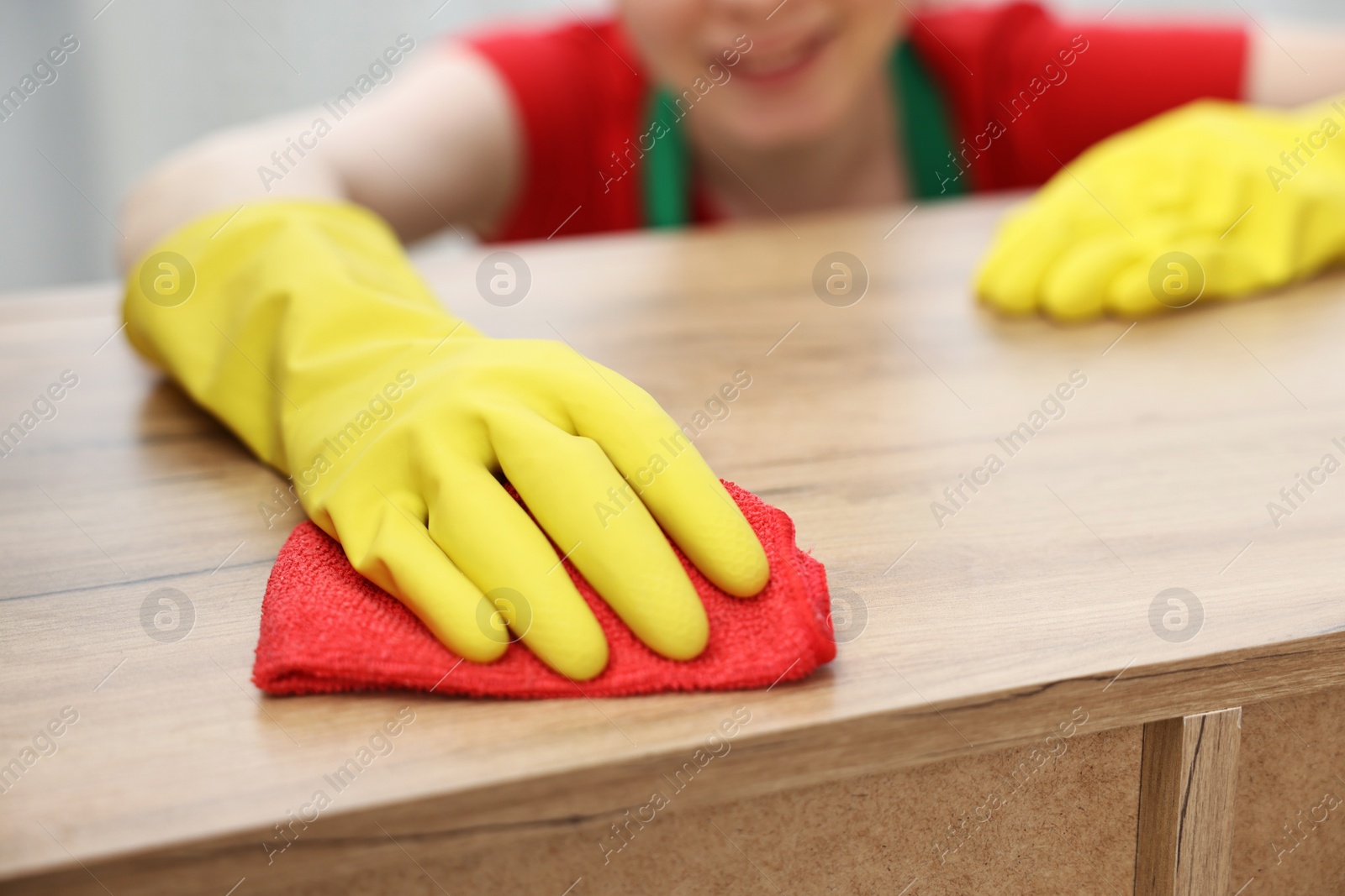 Photo of Woman cleaning wooden table with rag at home, closeup