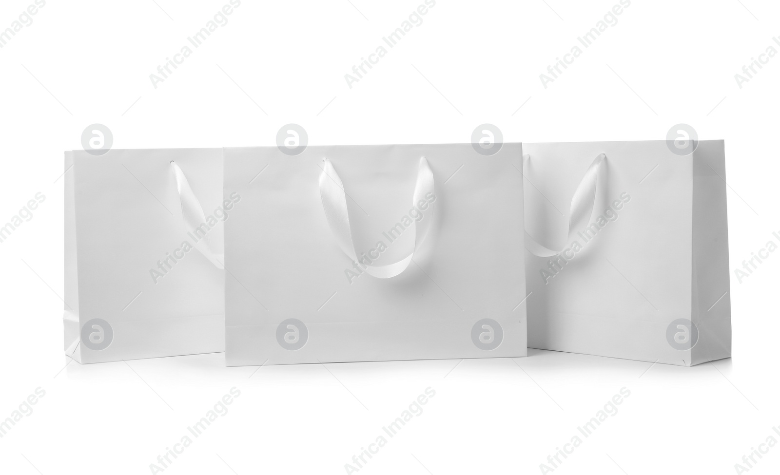 Photo of Paper shopping bags with ribbon handles on white background. Mockup for design