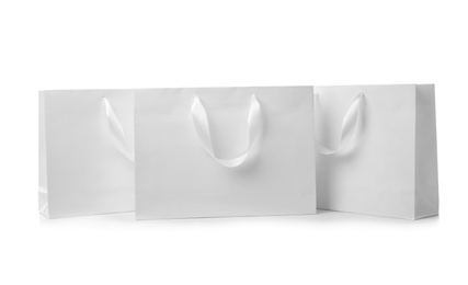 Photo of Paper shopping bags with ribbon handles on white background. Mockup for design