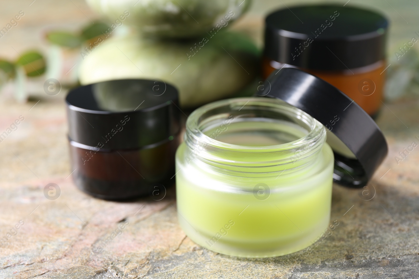 Photo of Jars of cream on textured table, closeup. Body care products