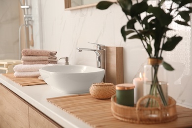 Photo of Fresh towels and beautiful branches near stylish vessel sink in bathroom. Interior design