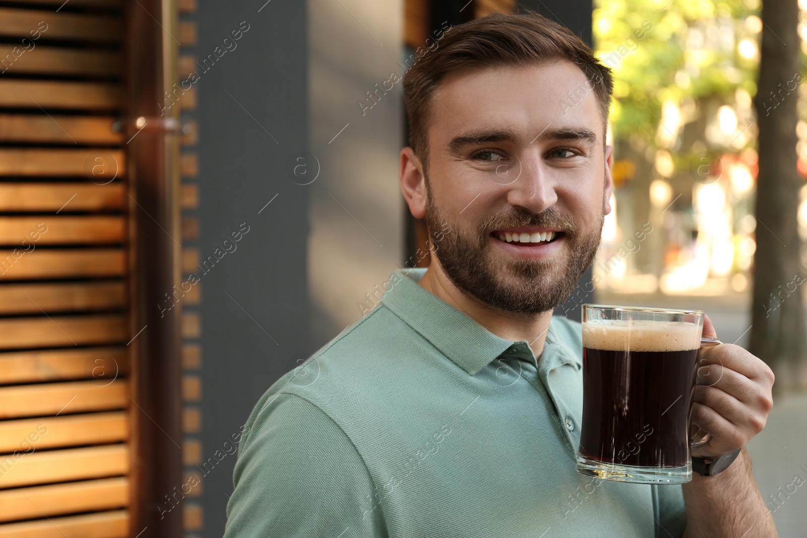 Photo of Handsome man with cold kvass outdoors. Traditional Russian summer drink