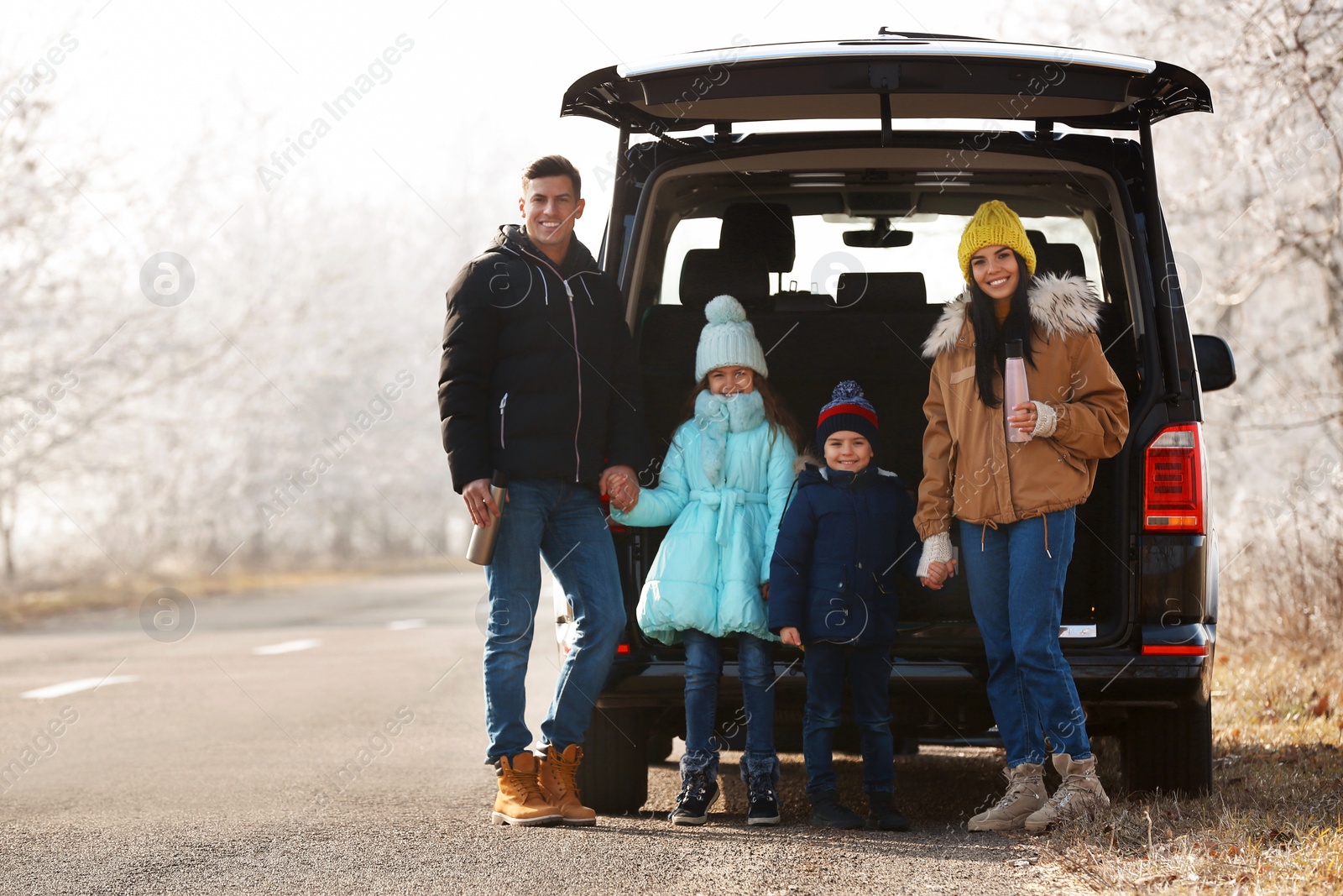 Photo of Happy family with little children near modern car on road