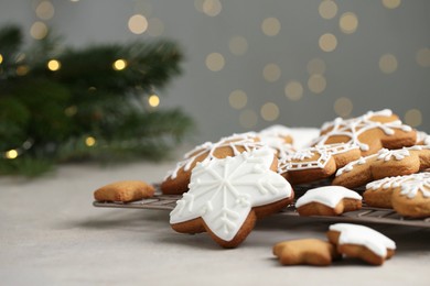 Photo of Tasty Christmas cookies with icing on table against blurred lights. Space for text