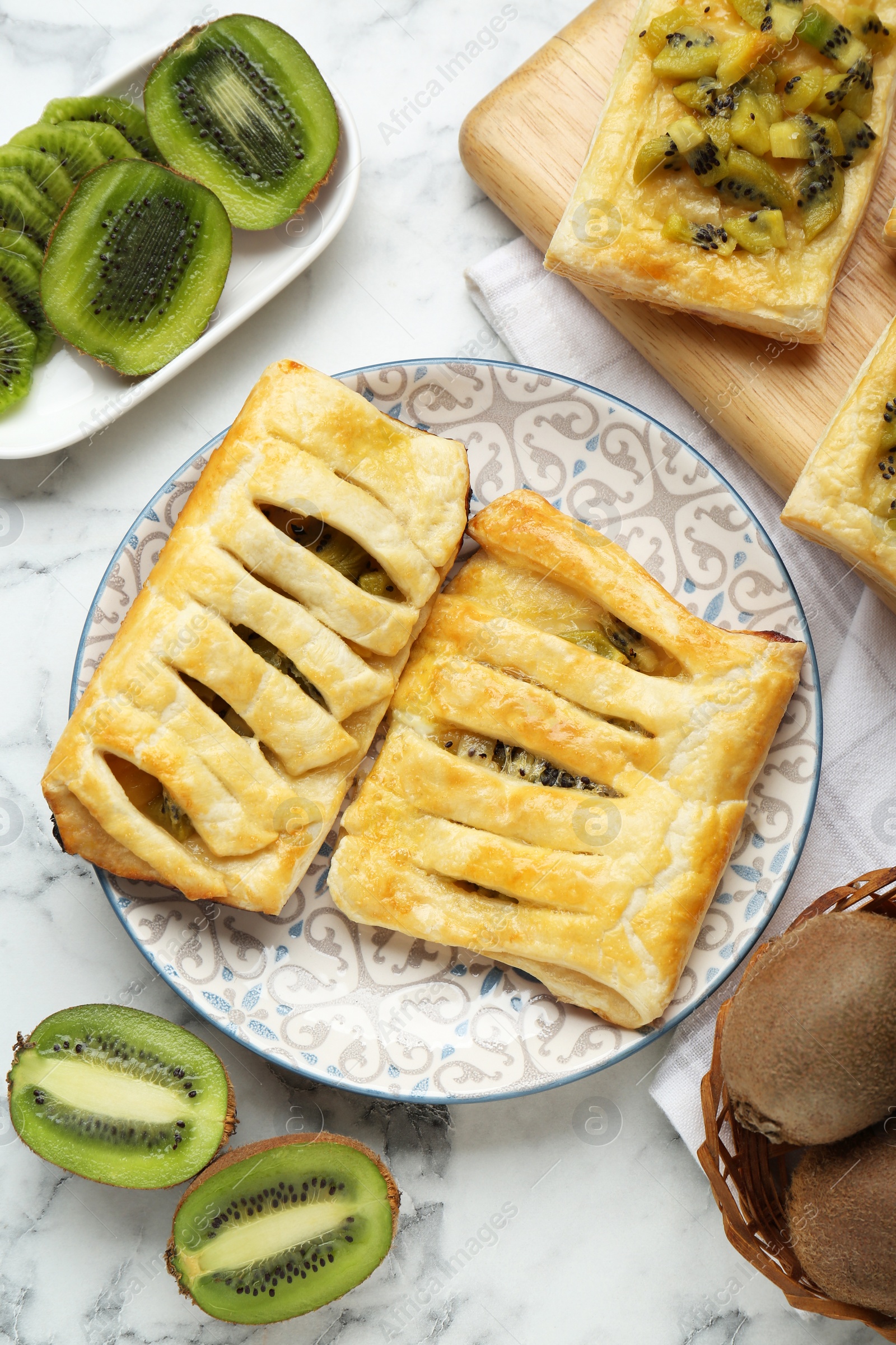 Photo of Fresh tasty puff pastry with kiwi on white marble table, flat lay
