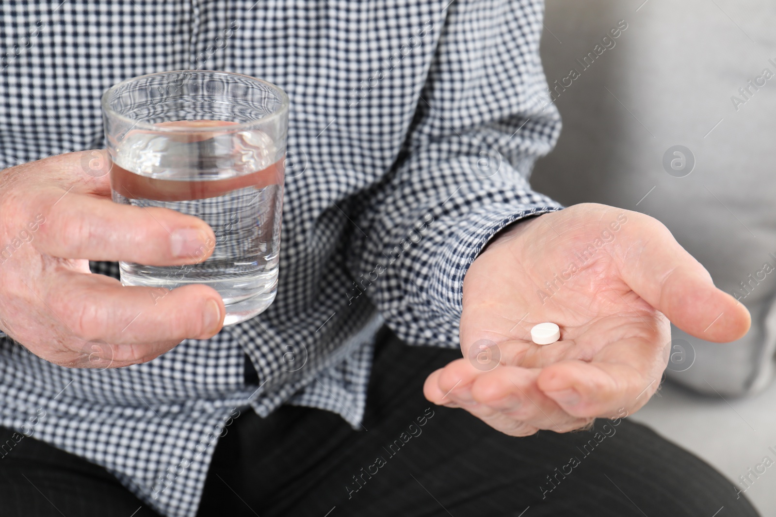 Photo of Senior man holding pill and glass of water, closeup