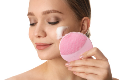 Photo of Young woman washing face with brush and cleansing foam on white background. Cosmetic products