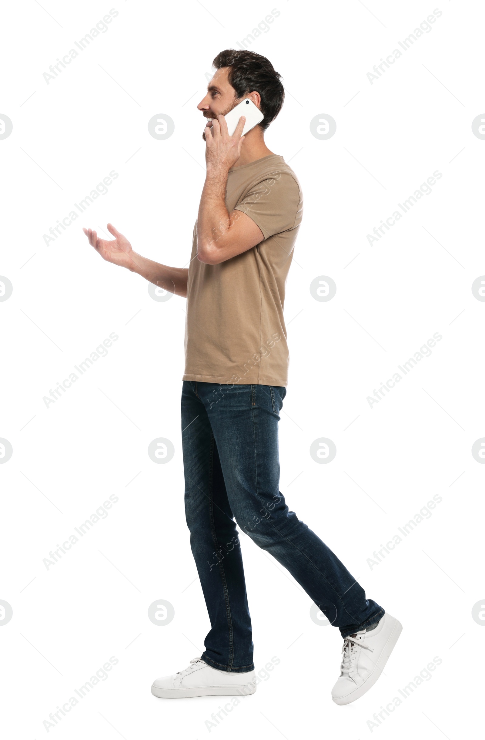 Photo of Handsome man talking on smartphone while walking against white background