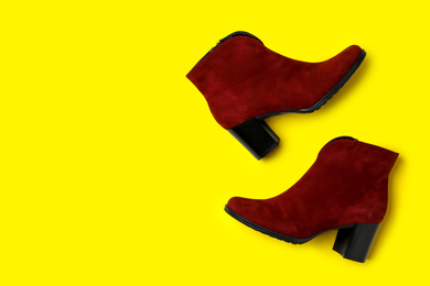 Photo of Stylish red female boots on yellow background, flat lay. Space for text