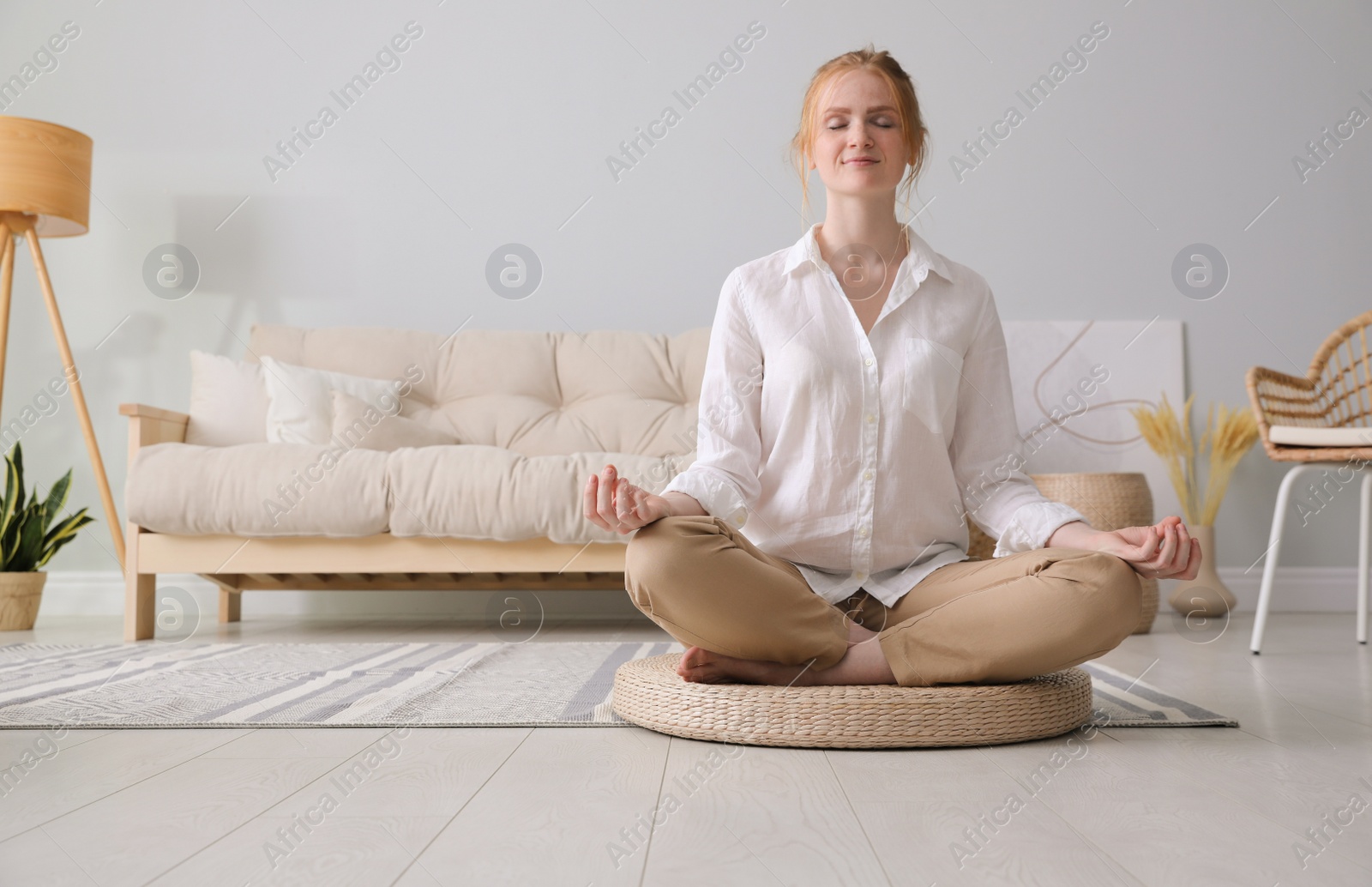 Photo of Woman meditating on wicker mat at home. Space for text