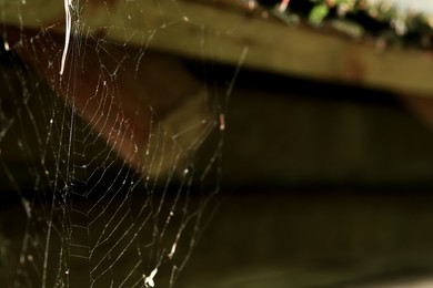 Photo of Cobweb on wooden building outdoors, closeup. Space for text