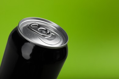Photo of Black can of energy drink on green background, closeup. Space for text