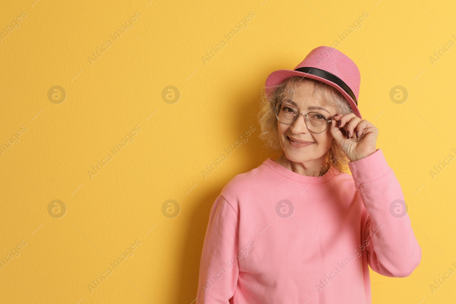 Photo of Portrait of mature woman in hipster outfit on color background. Space for text