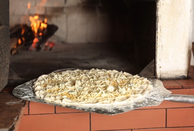 Photo of Putting pizza into oven in restaurant kitchen
