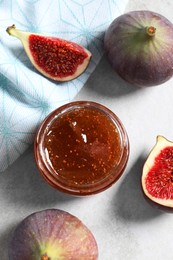 Photo of Jar of tasty sweet jam and fresh figs on light table, flat lay