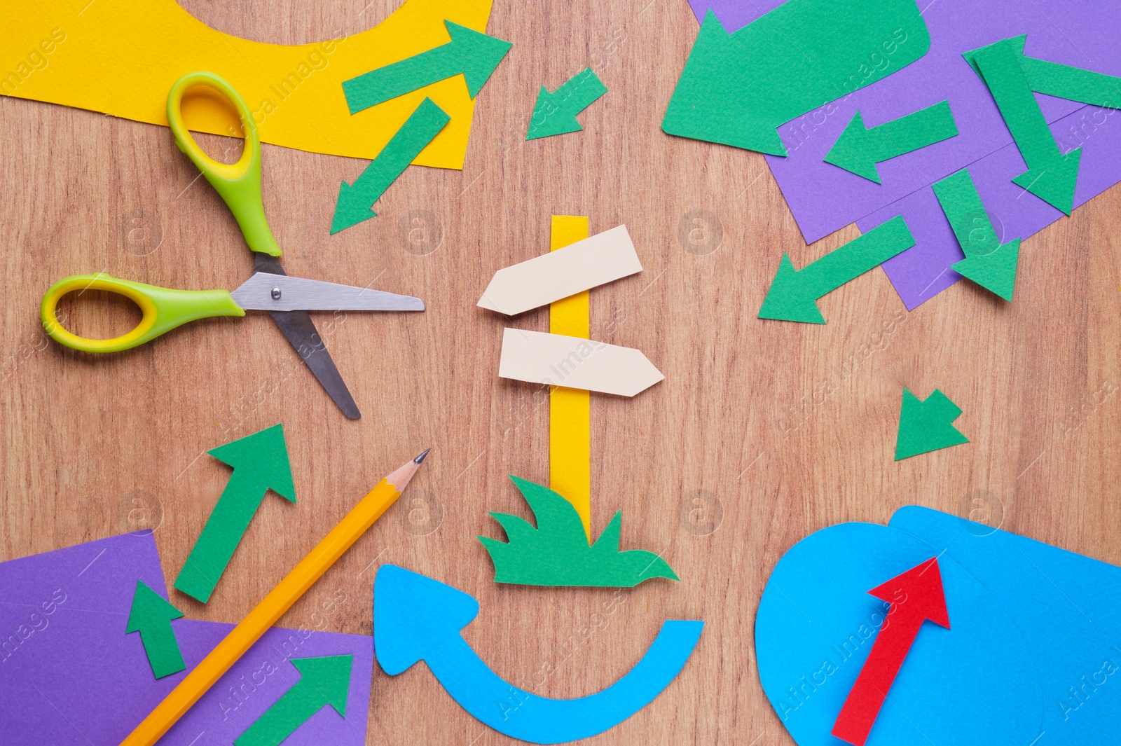 Photo of Scissors and different paper figures on wooden table, flat lay. Space for text