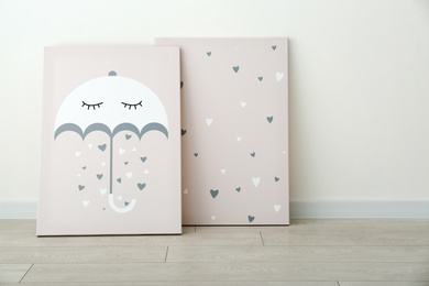 Adorable pictures of umbrella and hearts on floor near white wall. Children's room interior elements