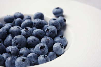 Photo of Juicy and fresh blueberries in white plate, closeup