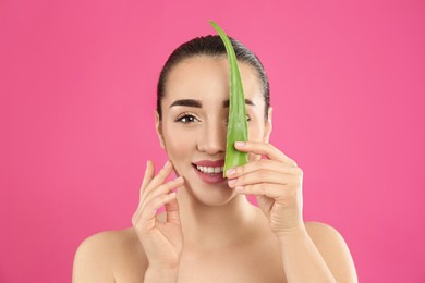 Photo of Young woman with aloe vera leaf on pink background