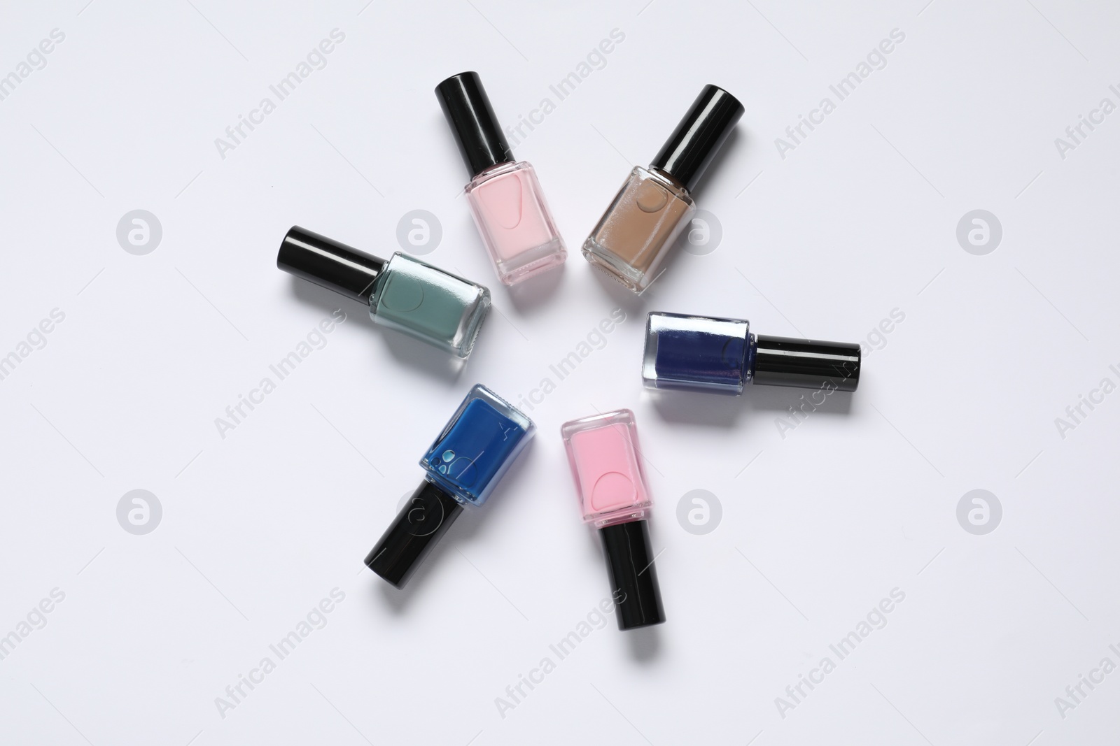 Photo of Nail polishes on white background, flat lay