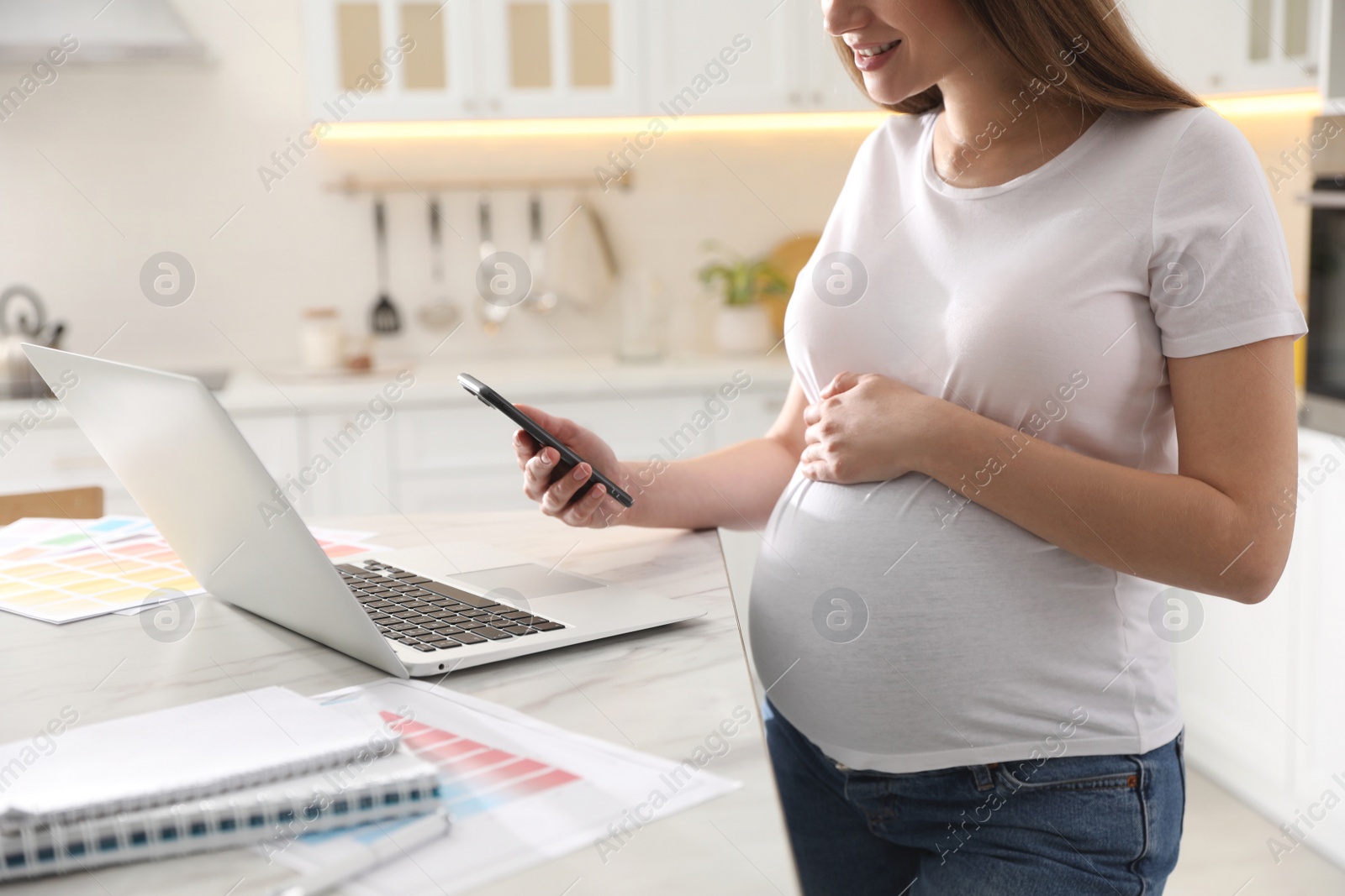 Photo of Pregnant woman working in kitchen at home, closeup. Maternity leave