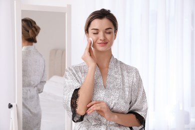 Photo of Beautiful young woman cleaning her face in room