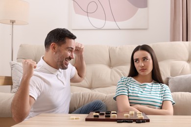 Photo of Couple playing checkers at table in room