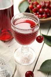 Delicious cherry wine with ripe juicy berries on white wooden table