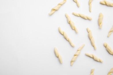 Uncooked trofie pasta on white background, flat lay. Space for text
