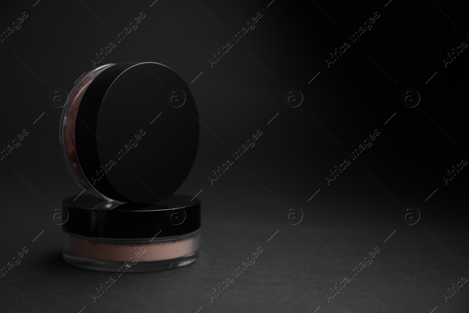 Photo of Jars of face powders on black background, closeup. Space for text